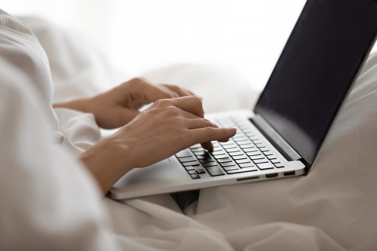 Close,Up,Young,Woman,Using,Computer,In,Bed,After,Waking
