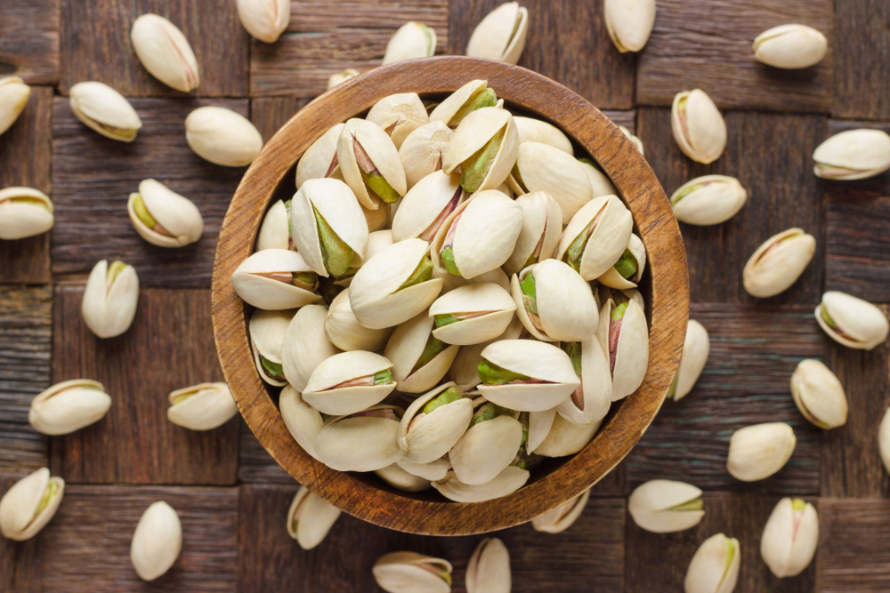 Pistachio,In,Shell,Nuts,In,Bowl,On,Wooden,Table,Background 